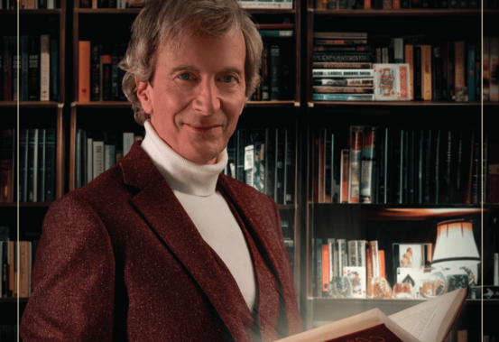 Alain Choquette, un livre à la main, devant une bibliothèque