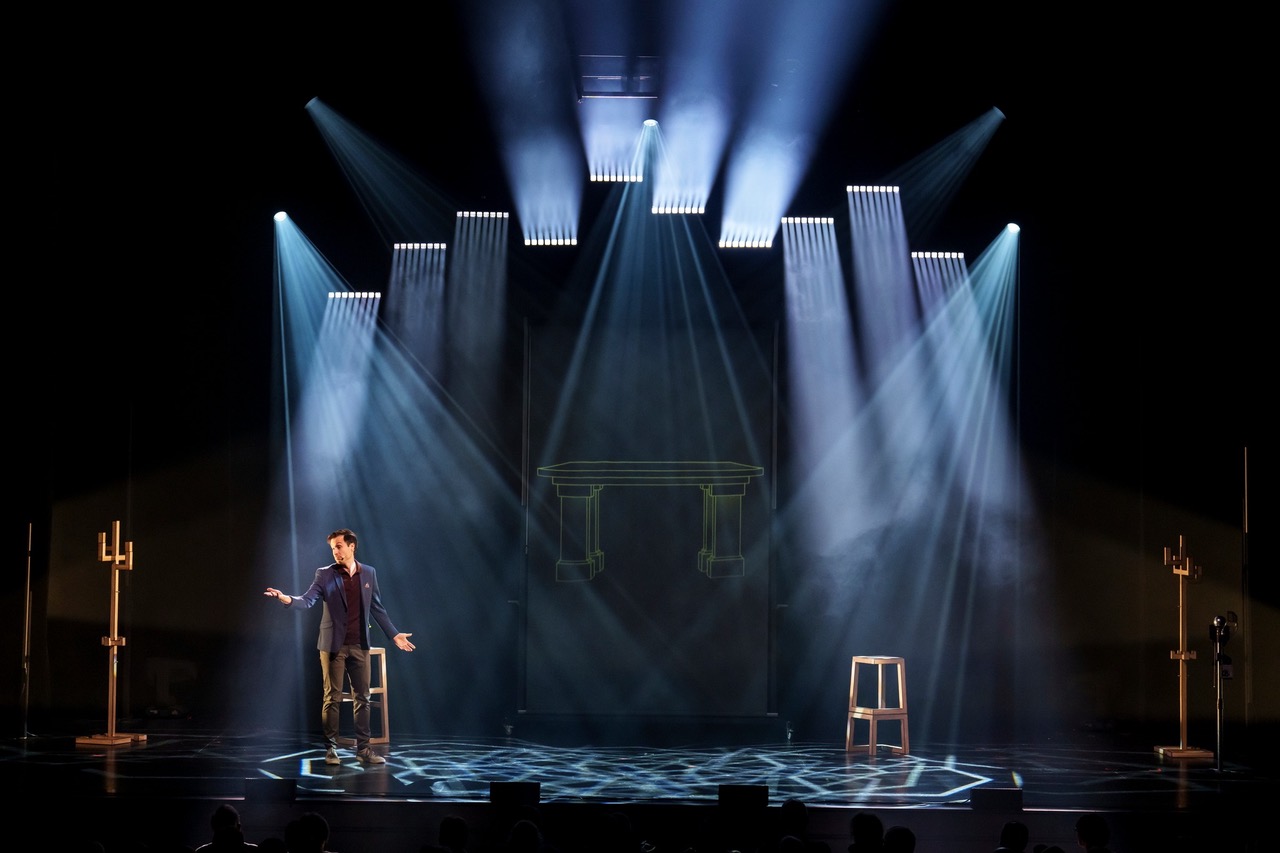 Luc Langevin en spectacle, sur scène, avec veston bleu